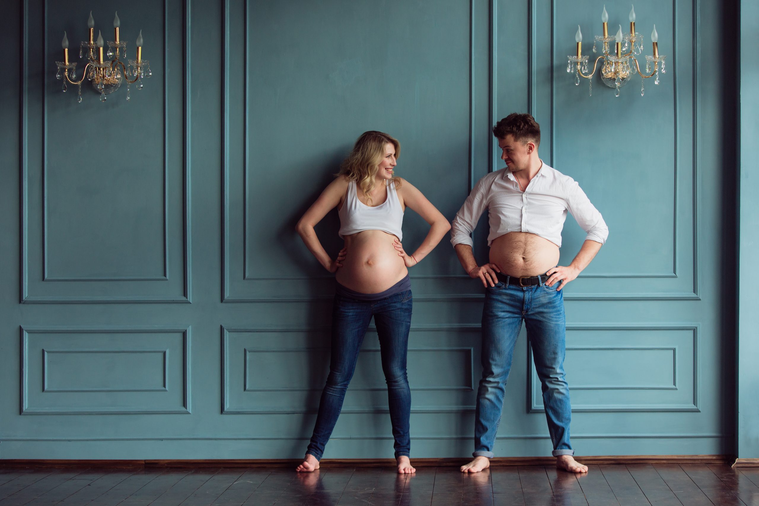 Pregnant couple in humorous pose both showing their bellies
