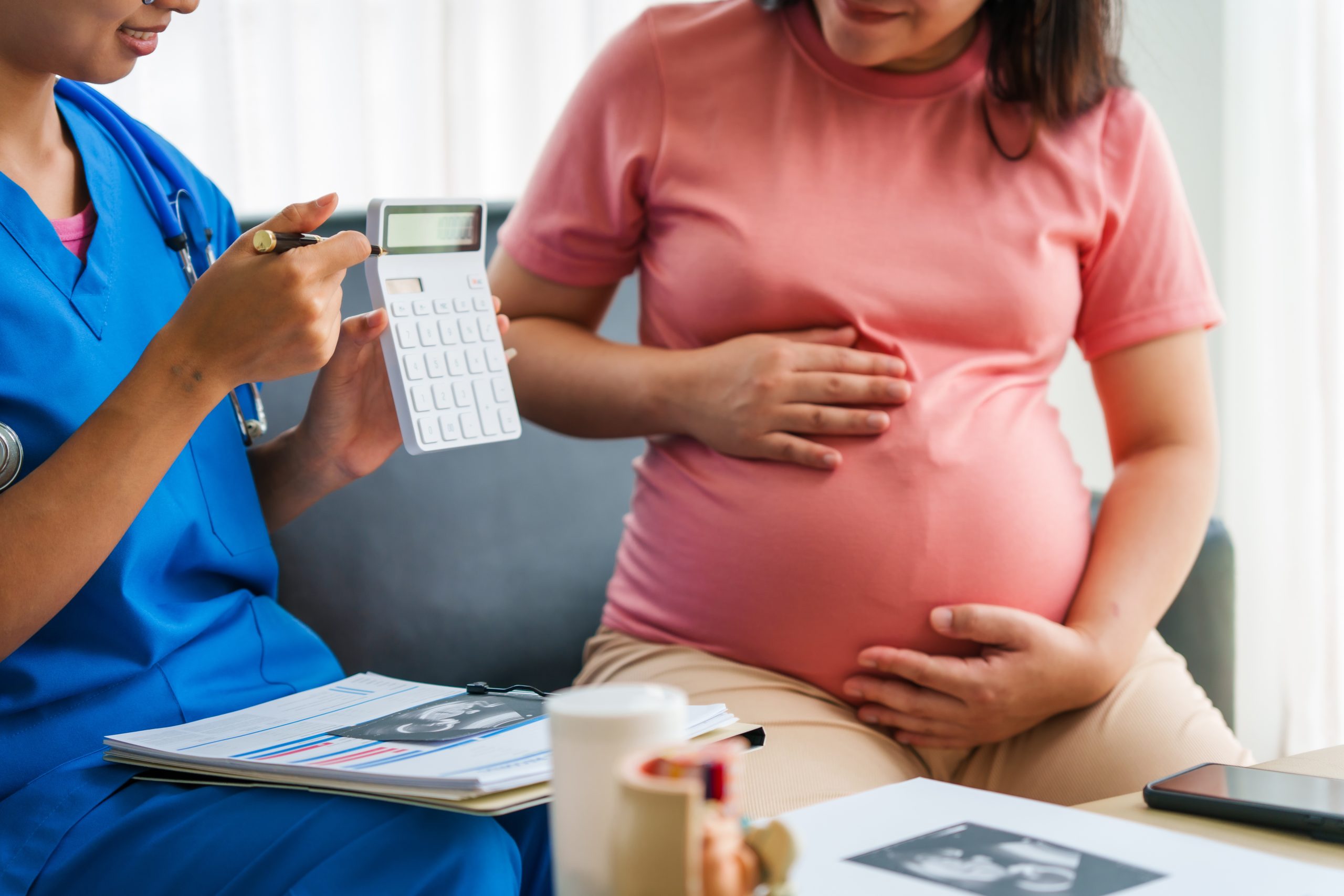 lady wearing pink top holding her pregnancy bump at antenatal appointment