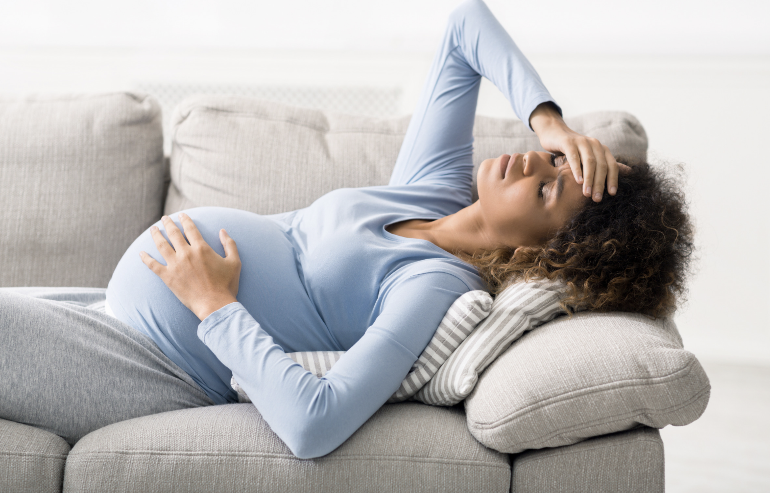 black pregnant woman laying down with hand on head