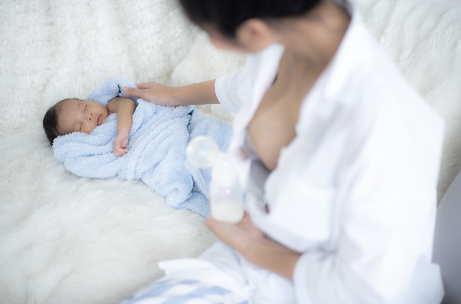 mum pumping breastmilk while cradling baby