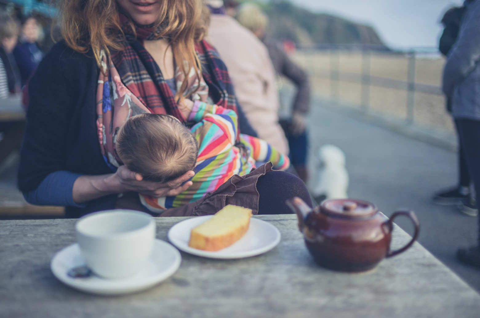 woman breastfeeding while sat at table eating food