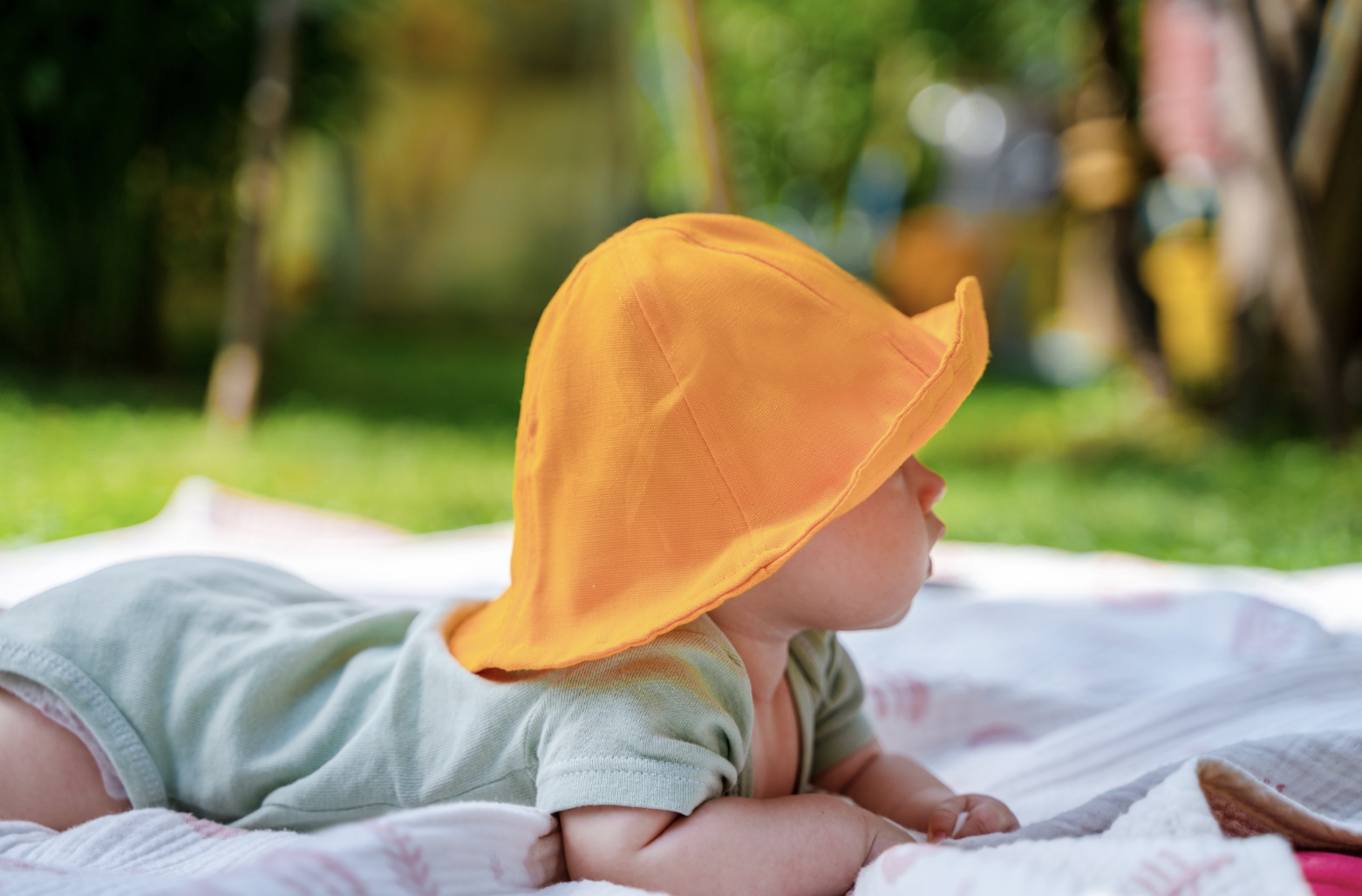 baby sat in the sun with a hat on