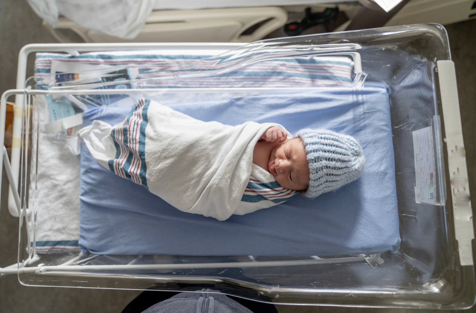 newborn baby laying in hospital cotbed