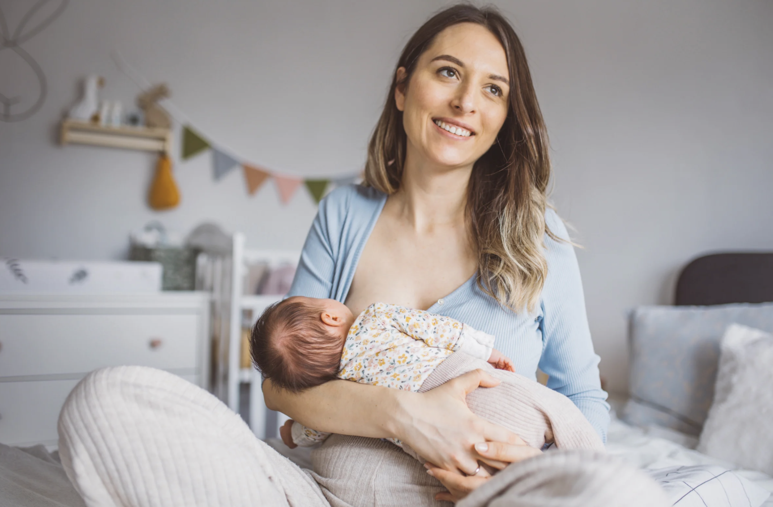 new mum breastfeeding while smiling
