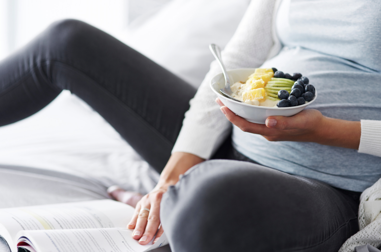 pregnant woman holding a bowl of fruit